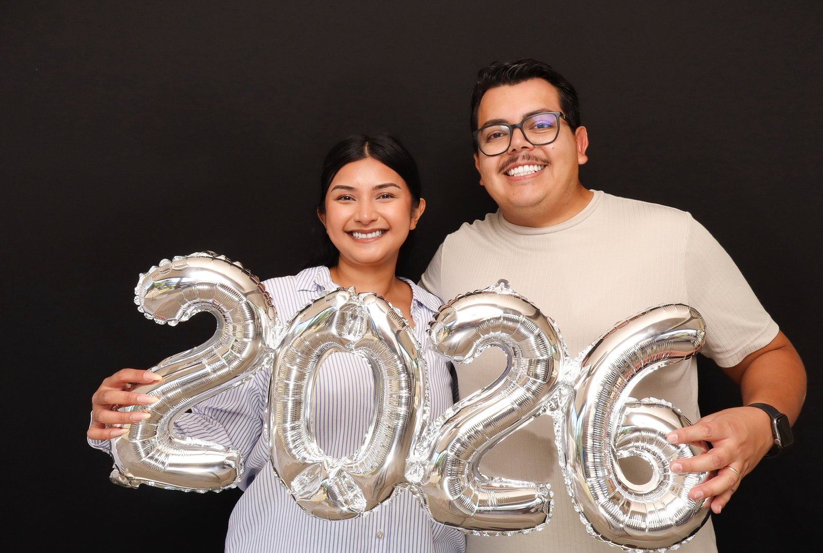 Permata and Melvin of 29PM Photo Booth holding silver 2026 balloons