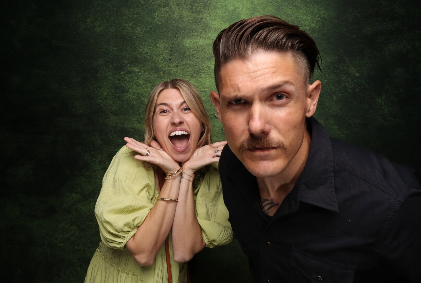 Two guests posing at a 29PM photo booth with a textured green backdrop