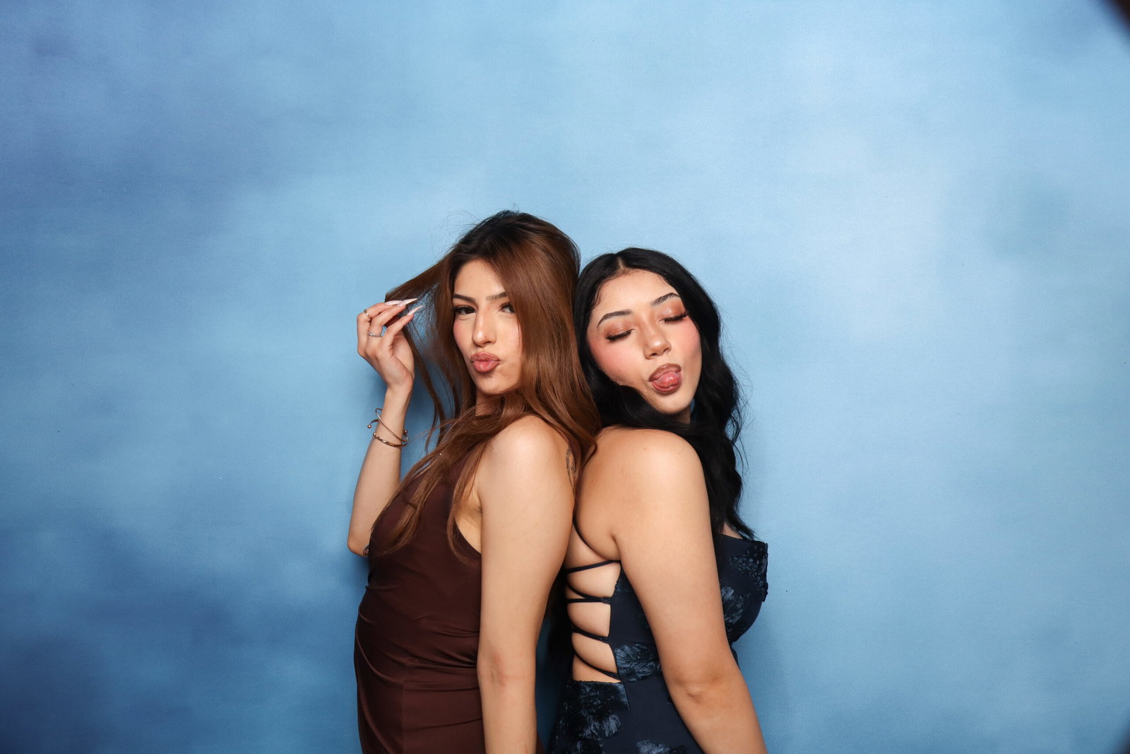 Two friends posing together against a blue backdrop at a 29PM Modern Open-Air photo booth