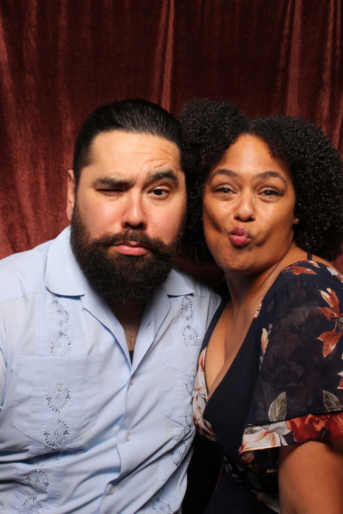 Couple posing in a 29PM photo booth with a red velvet backdrop