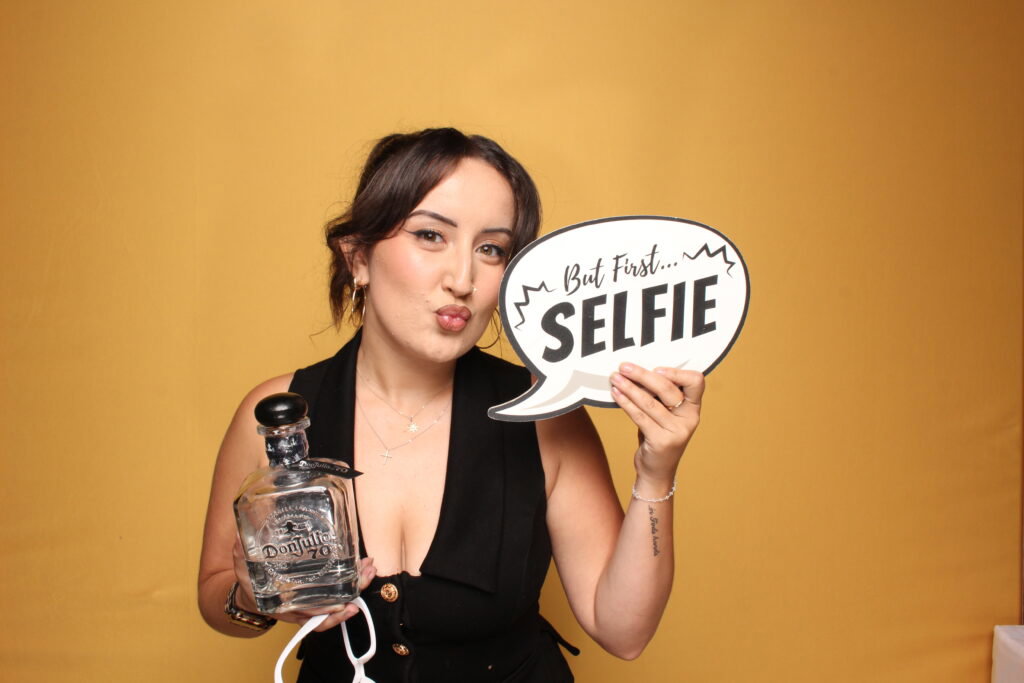 Guest posing with a selfie prop against a yellow 29PM photo booth backdrop