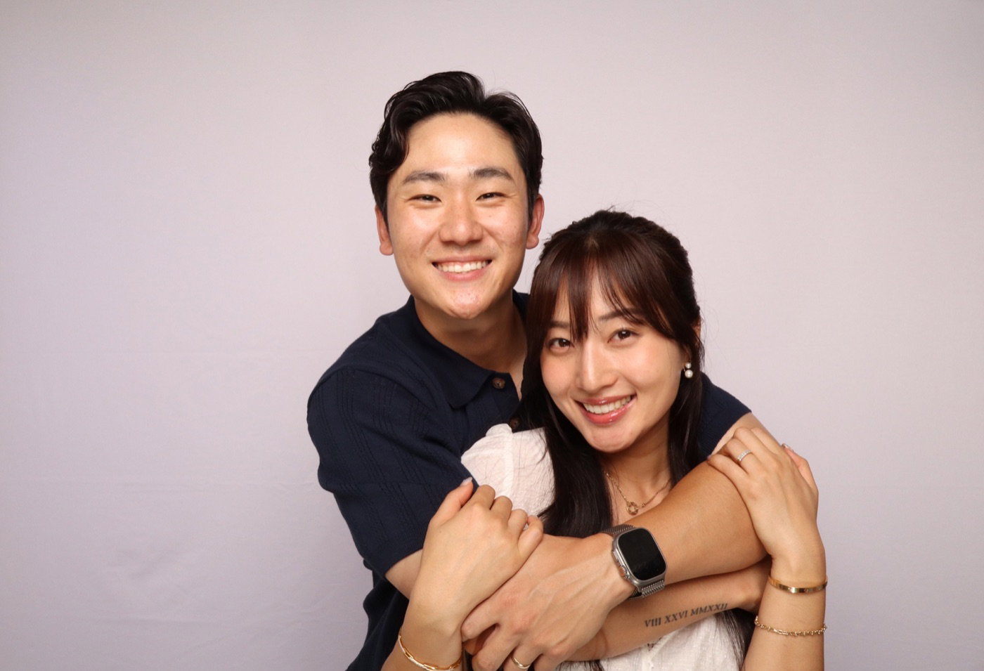 Smiling couple posing together against a blush Glam Booth backdrop